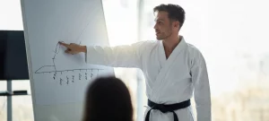Kampfsporttrainer erklärt Wachstumsdiagramm auf Flipchart als Symbol für strategische Preisgestaltung und Umsatzoptimierung in der Kampfsportschule