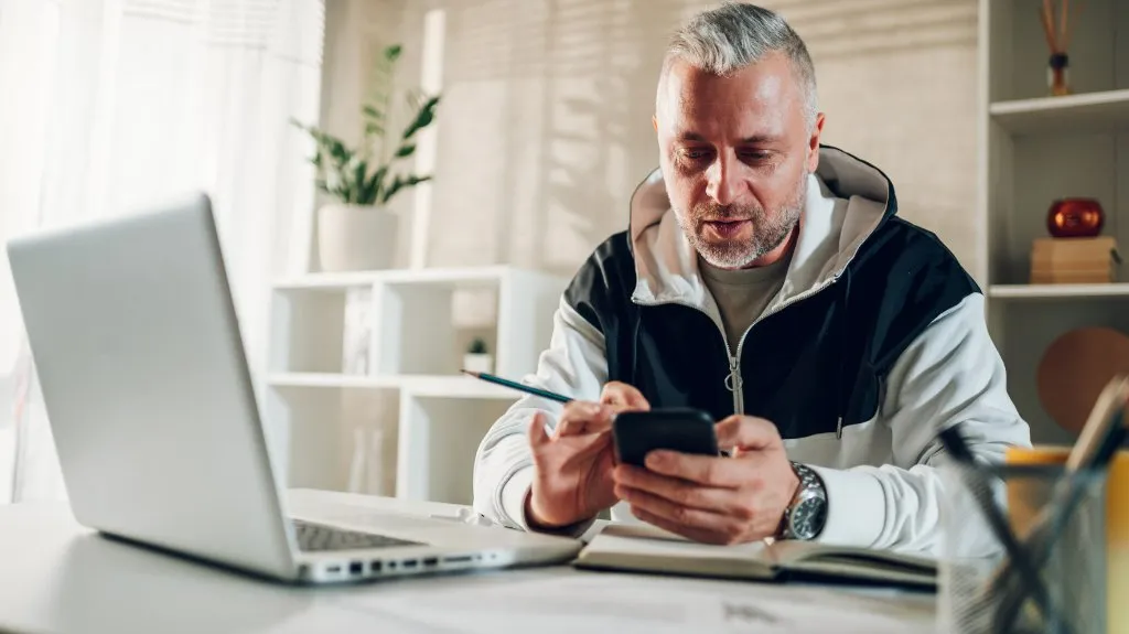 Trainer koordiniert Anfragen über Smartphone und Laptop, um Administration zu automatisieren und Prozesse effizienter zu steuern.