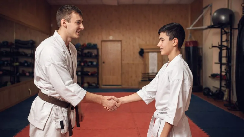 Trainer begrüßt neuen Schüler im Probetraining zur Kundengewinnung für eine Kampfsportschule