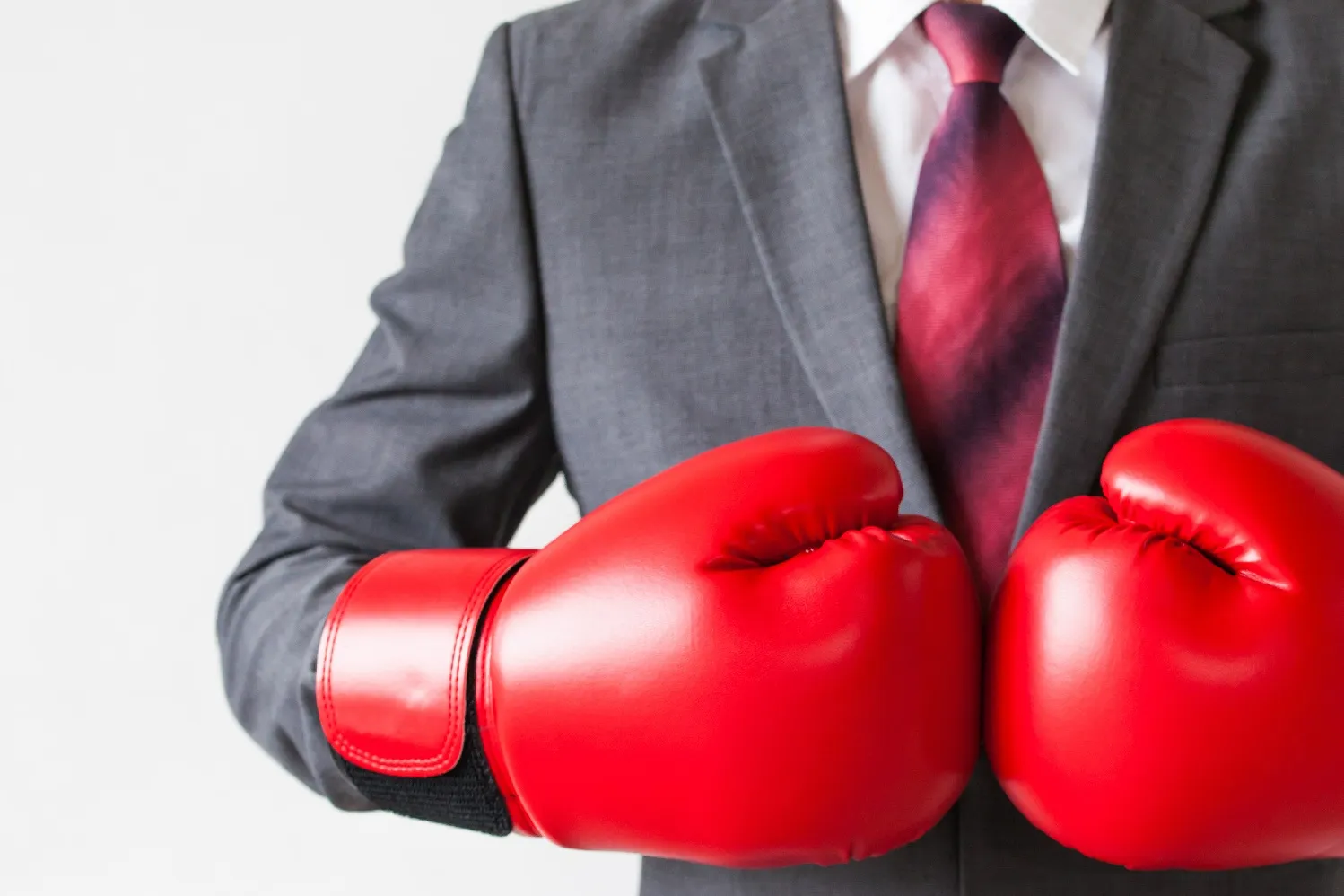 Person im Business-Outfit mit Boxhandschuhen als Symbol für Team Building und Selbstverteidigung im Unternehmenskontext